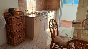 Una cocina con ventilador, cestas de mimbre, una mesa de comedor con sillas y vistas al exterior.