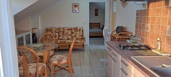 Un espacio habitable compacto con comedor, kitchenette y un dormitorio.