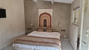 A bedroom with a bed, a wall tapestry, bedside lamps, and a window.