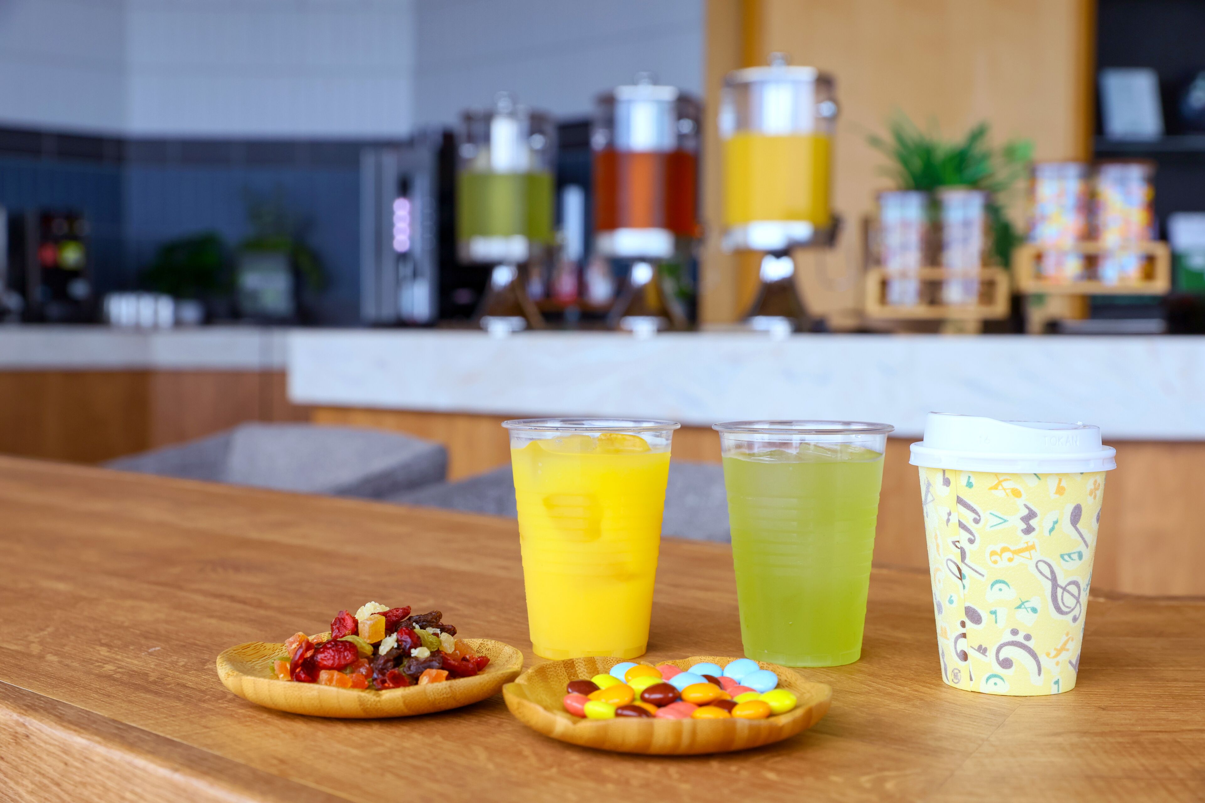 A wooden table with two drinks, a dessert, and a coffee cup.