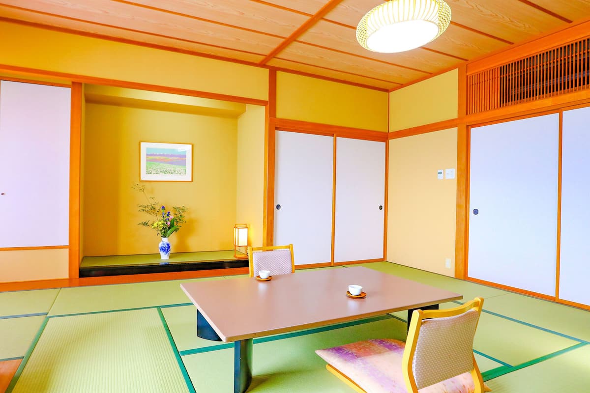 Una habitación japonesa tradicional con suelo de tatami, una mesa baja y puertas correderas shoji.