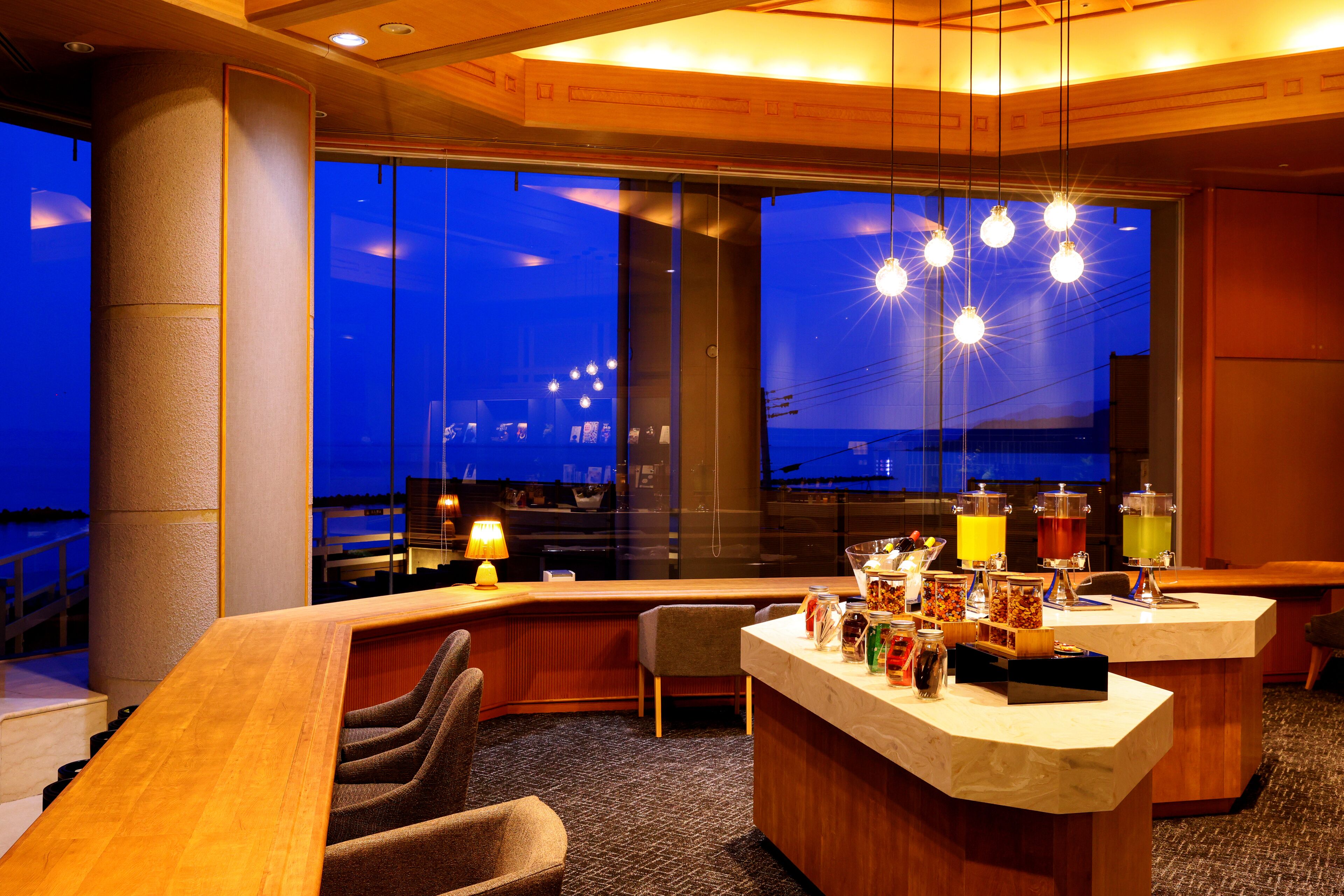 Un bar de hotel con un ventanal grande, una barra con varios artículos y una silla.