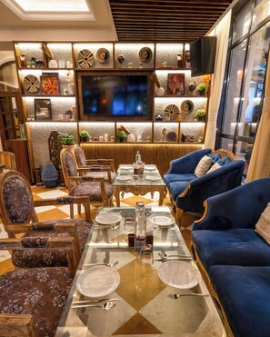 A well-appointed lounge with seating, a television, and decorative wall elements. - Arnna Hotel - Goregaon (Mumbai)