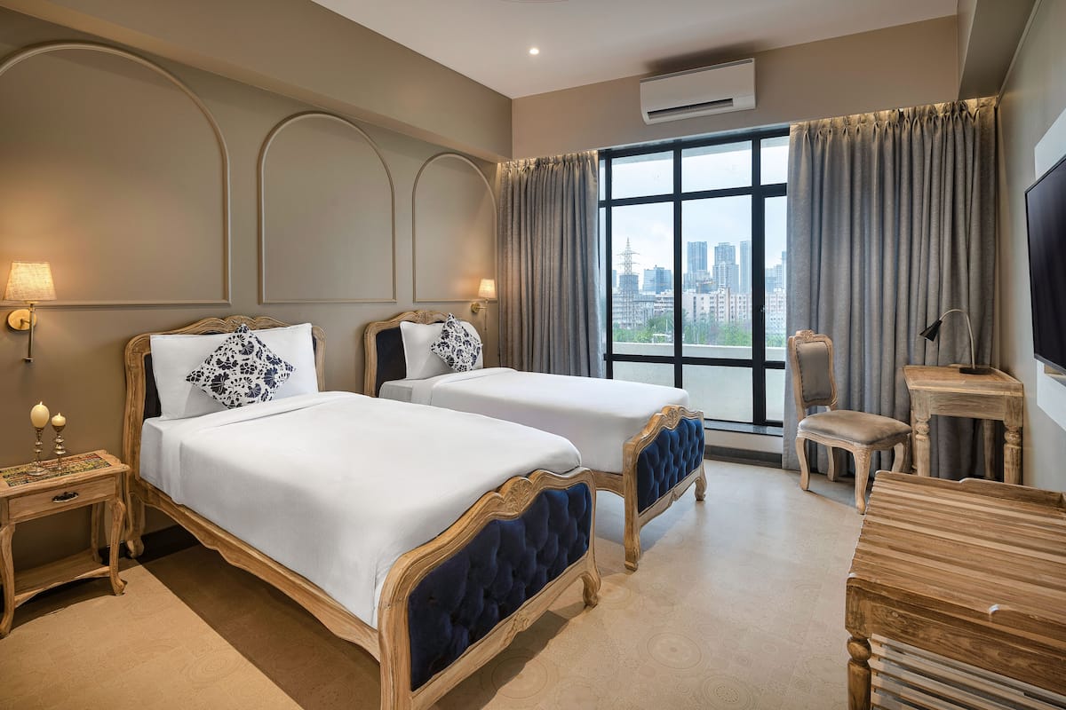 Quarto de hotel com duas camas, televisão, escrivaninha e uma cadeira.