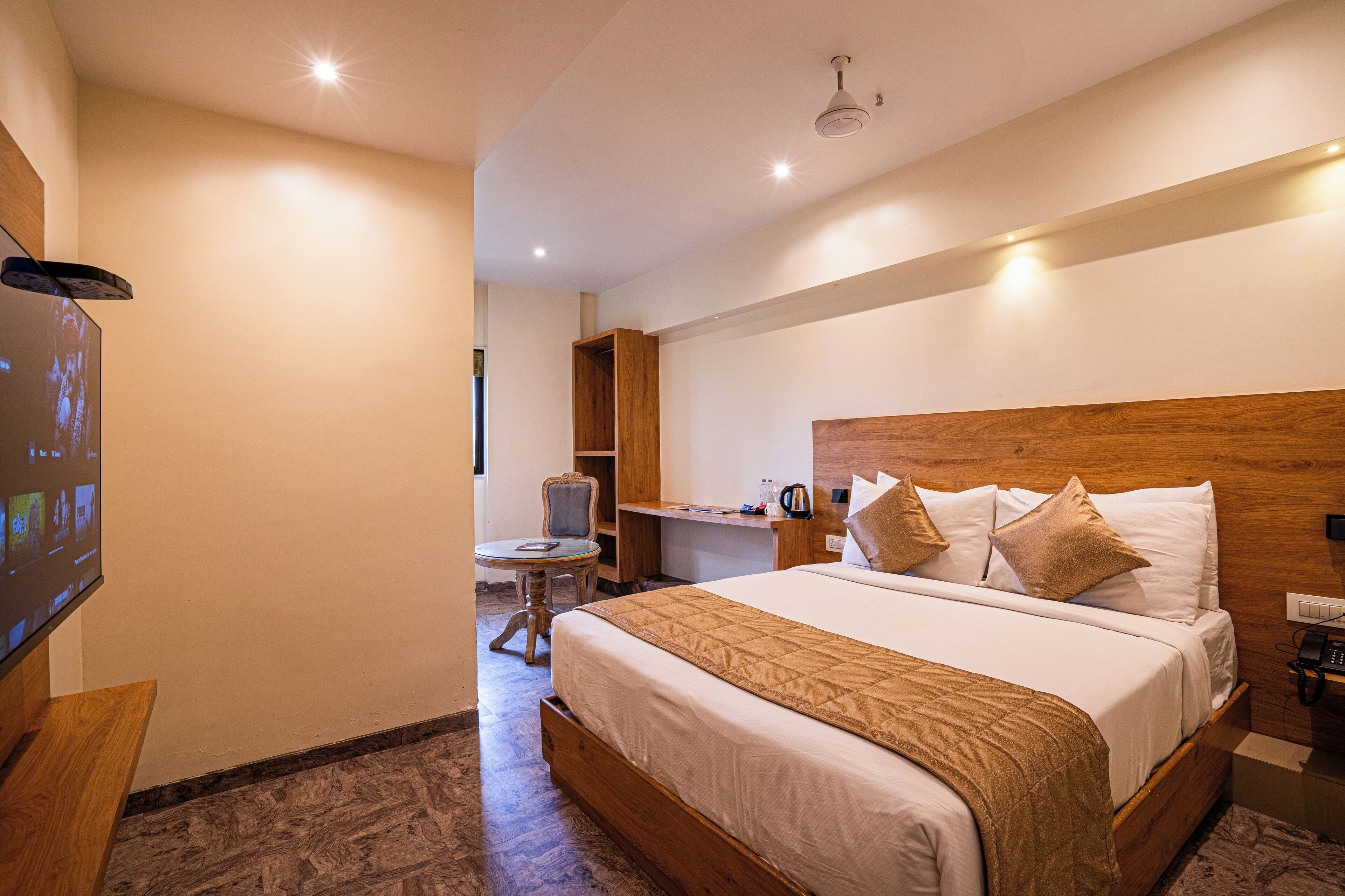 A hotel room with a large bed, a desk, a chair, and a television.