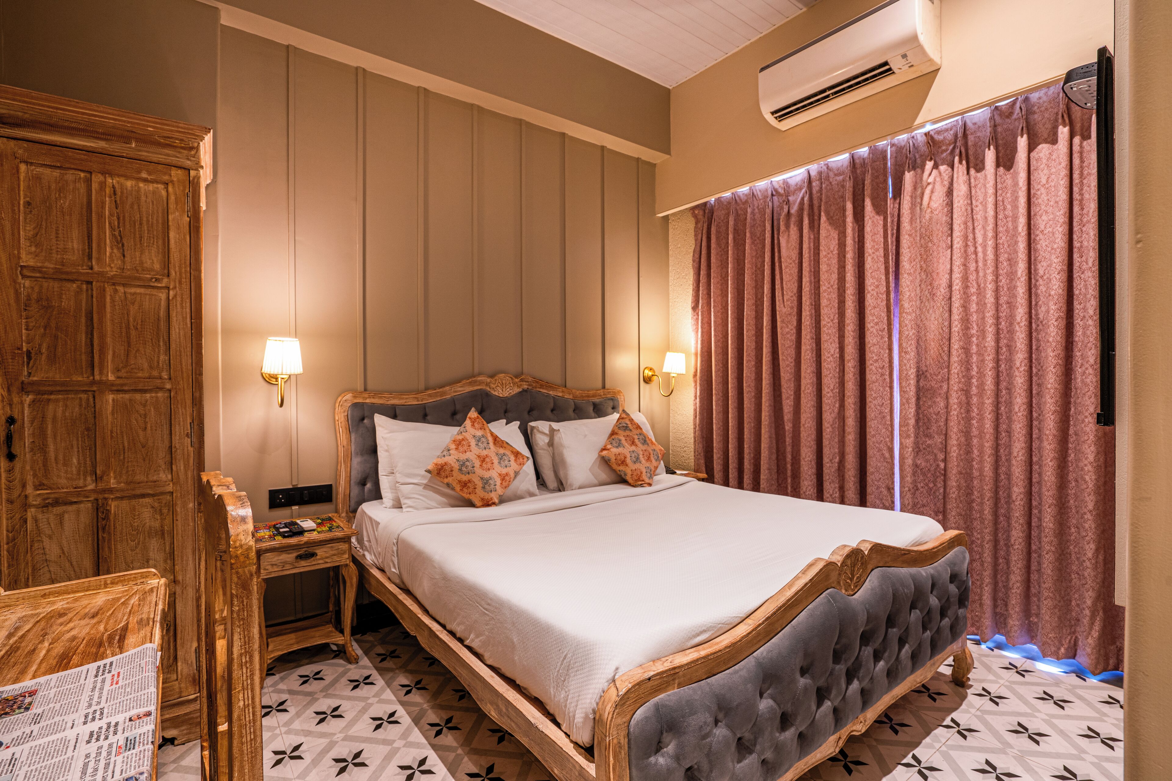 Een slaapkamer met een groot bed, een houten garderobe, twee nachtkastjes met lampen, en een vloer met een patroon.