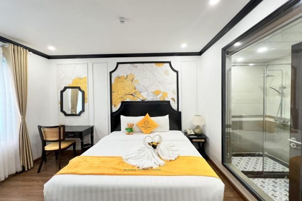 Une chambre d’hôtel avec un grand lit, un bureau, une chaise, un espace douche et une fenêtre.