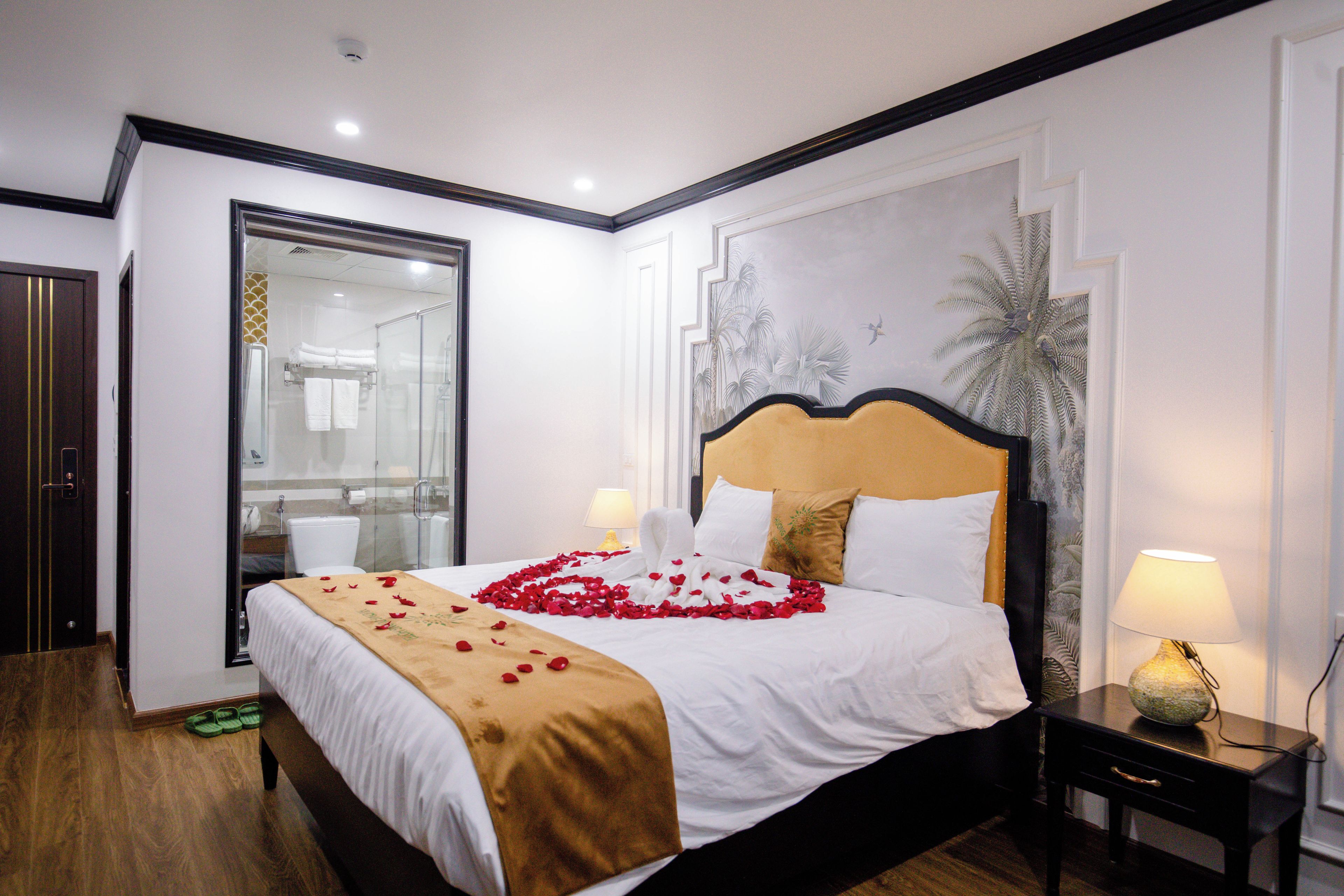 Een hotelkamer met een groot bed, een nachtkastje, een spiegel en een badkamer die door een open deur zichtbaar is.