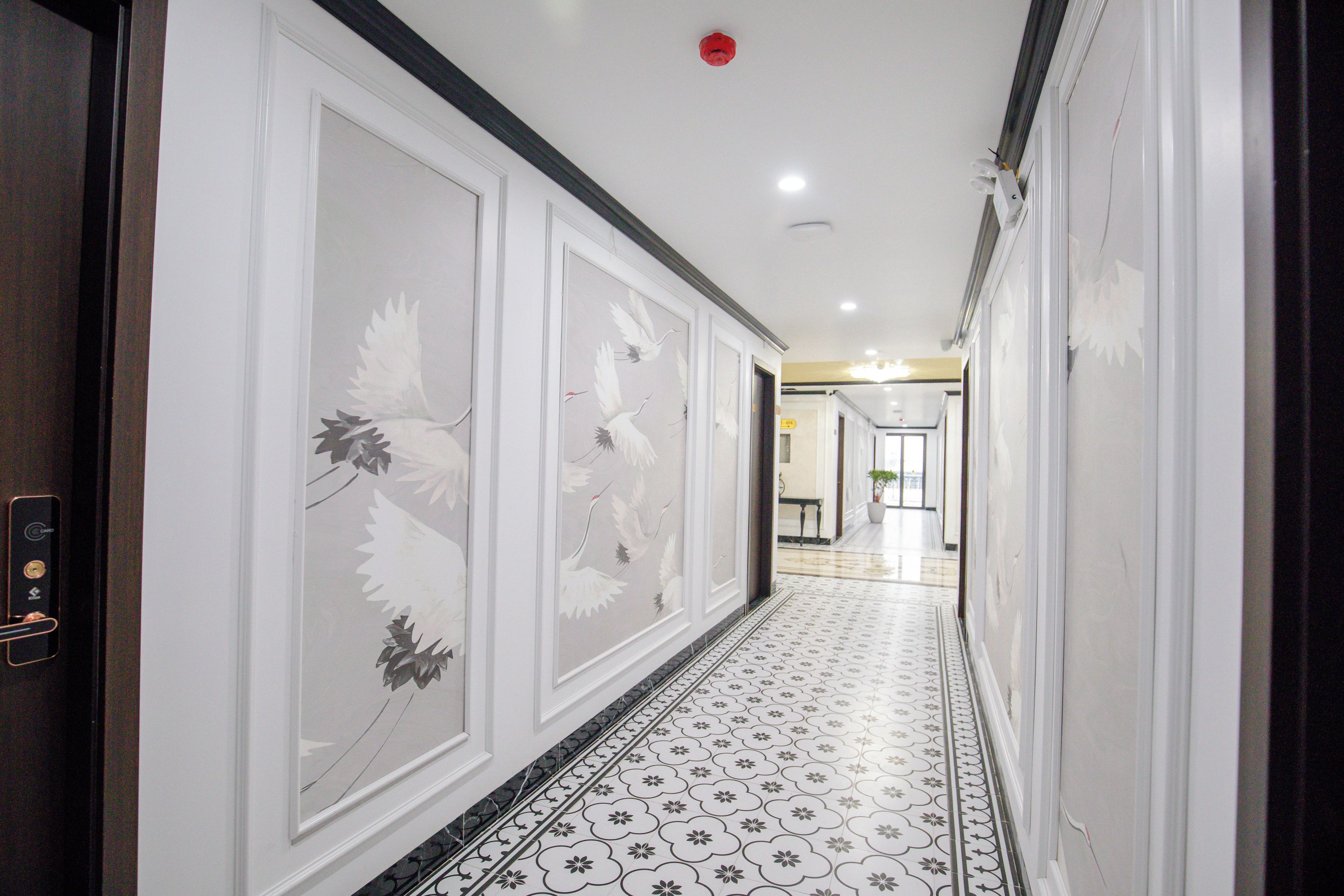 Un couloir doté d’un revêtement de sol à motifs et orné d’œuvres d’art murales représentant des oiseaux.