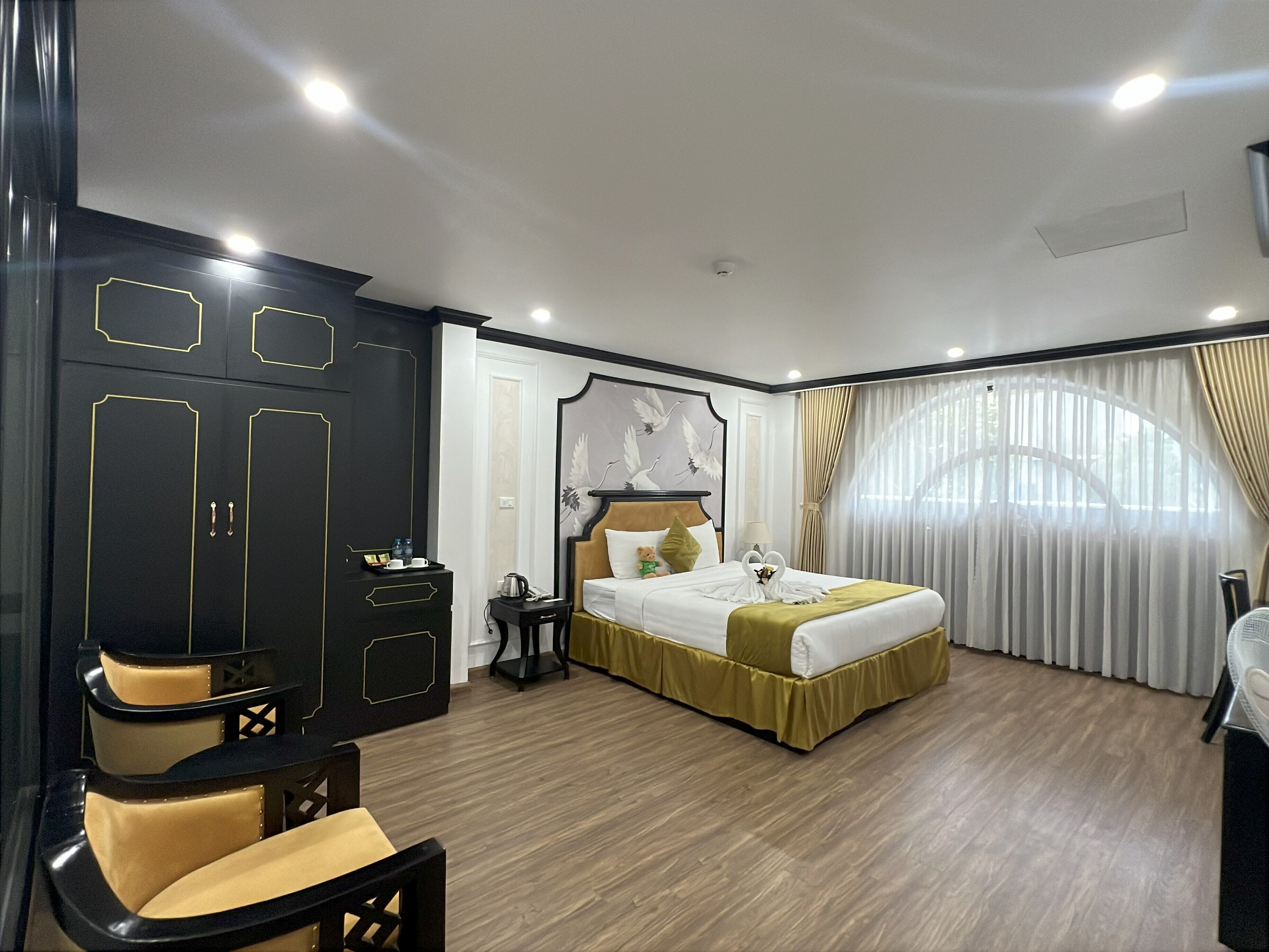 A hotel room with a bed, a wardrobe, a desk, and a chair.