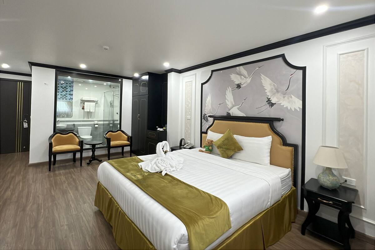 Quarto de hotel com uma cama grande, uma escrivaninha, uma cadeira e um espelho.