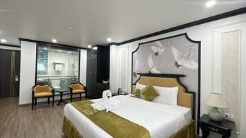 A hotel room with a large bed, a desk, a chair, and a mirror.