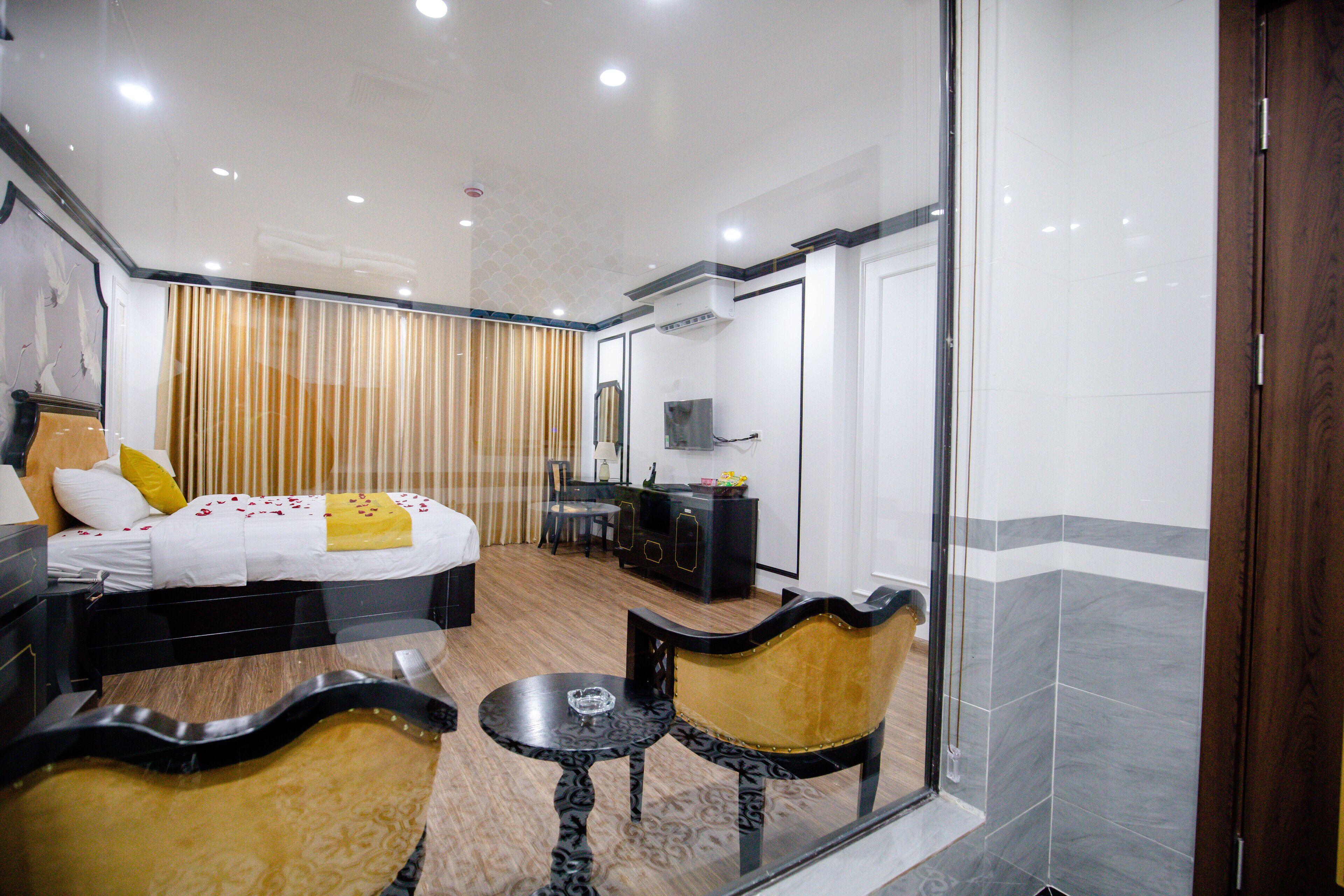 A hotel room with a bed, a desk, a chair, and a glass partition.
