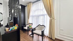A room with a wooden floor, a dining table with chairs, a decorative screen, and a window with curtains. - Huong Duong Hotel Thanh Hoa (Hac Thanh)