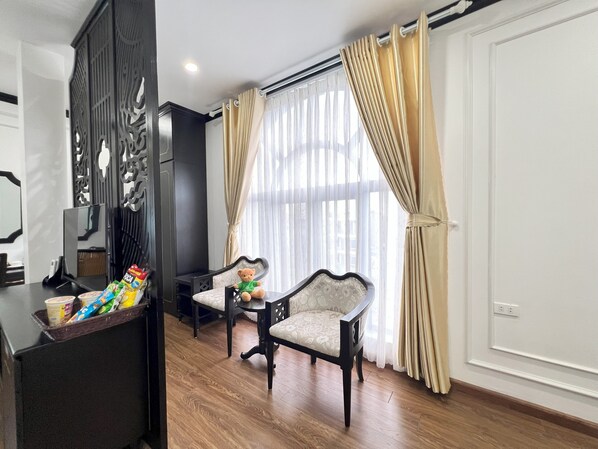 A room with a wooden floor, a dining table with chairs, a decorative screen, and a window with curtains. - Huong Duong Hotel Thanh Hoa (Hac Thanh)