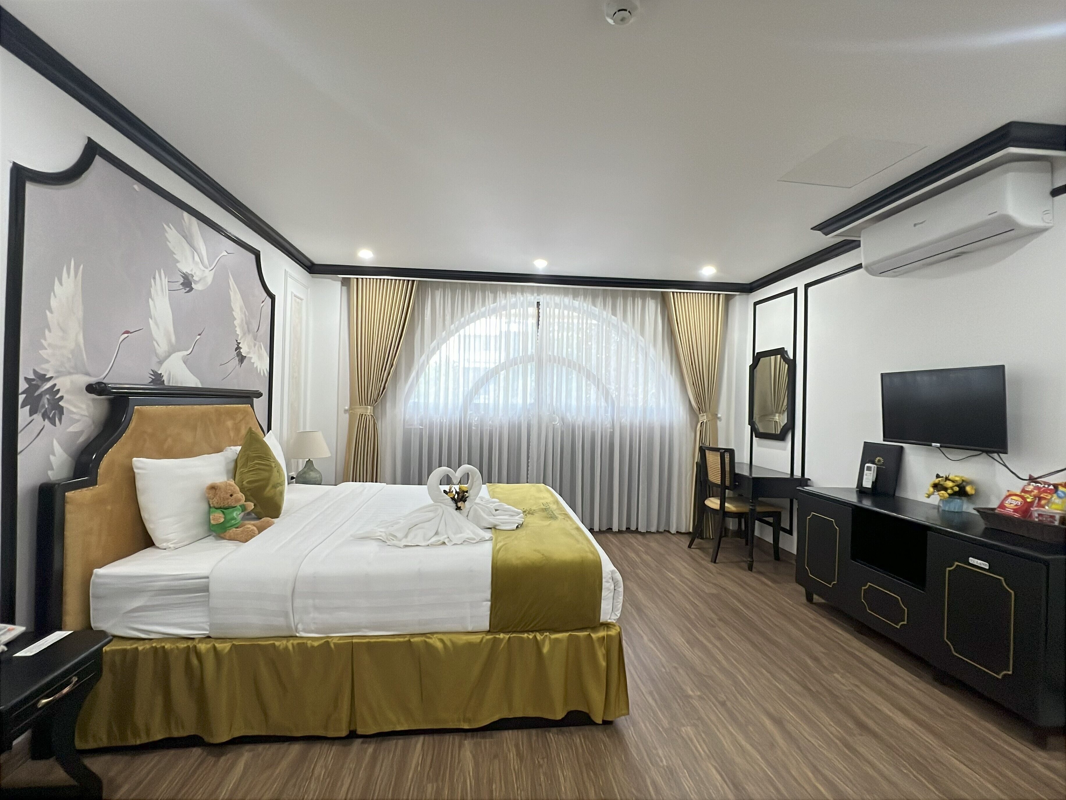 A hotel room with a bed, a desk, a TV, and a window with curtains.