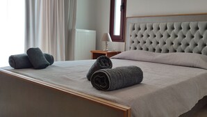 A neatly made bed with a tufted headboard, two bedside tables with lamps, and a window with curtains.