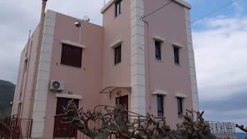 A multi-story building with a pink facade, multiple windows, and a visible air conditioning unit.