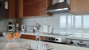 A modern kitchen with stainless steel appliances, wooden cabinets, and a marble countertop.