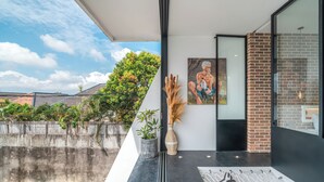 A modern interior with a glass wall, a painting, a potted plant, and a decorative vase. - Loft Erika (Canggu)