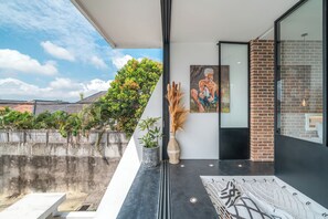 A modern interior with a glass wall, a painting, a potted plant, and a decorative vase.