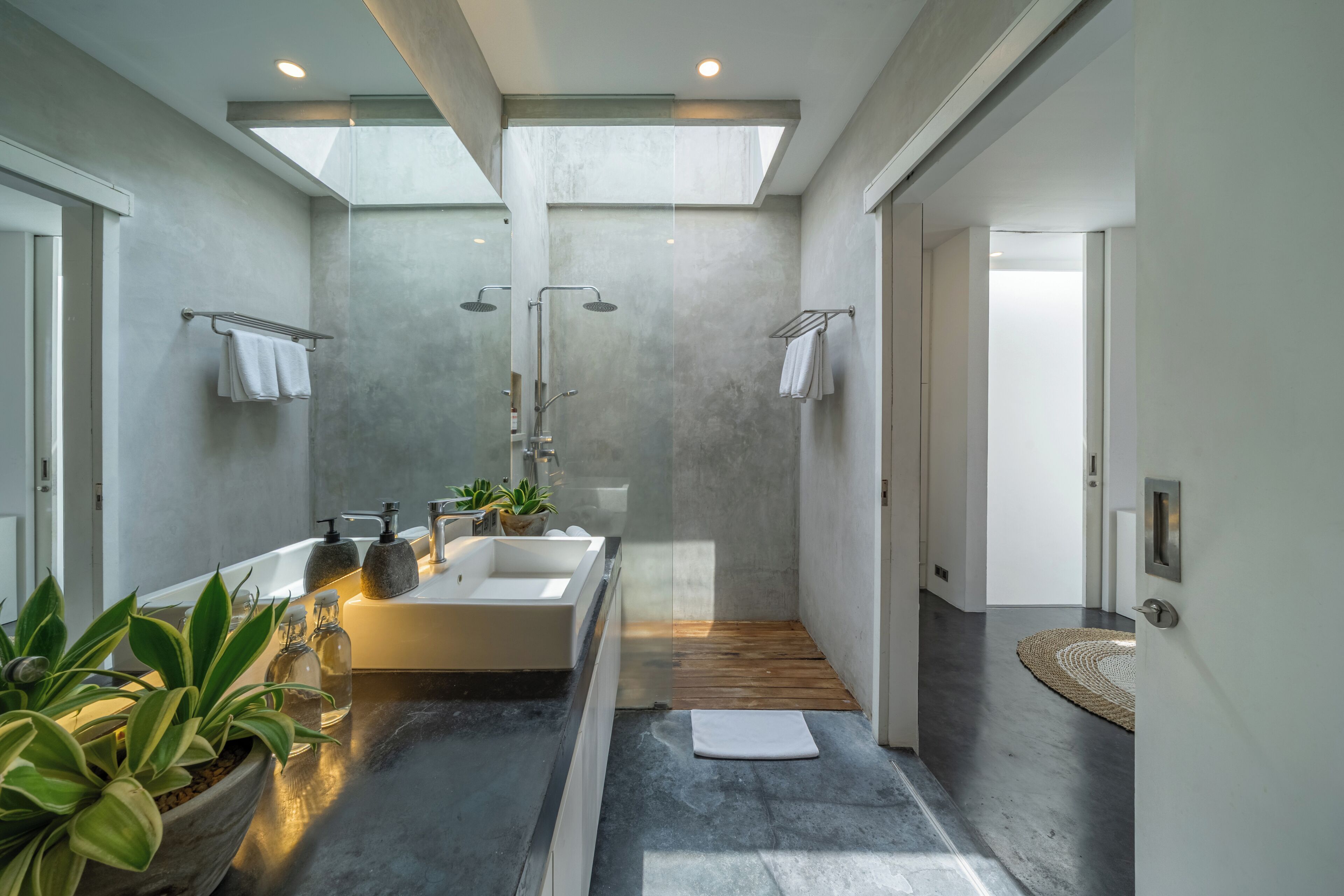 A modern bathroom with a skylight, a bathtub, a shower, and a sink.