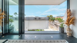 A modern room with a sliding glass door leading to a balcony, a potted plant, and a vase on the windowsill. - Loft Erika (Canggu)