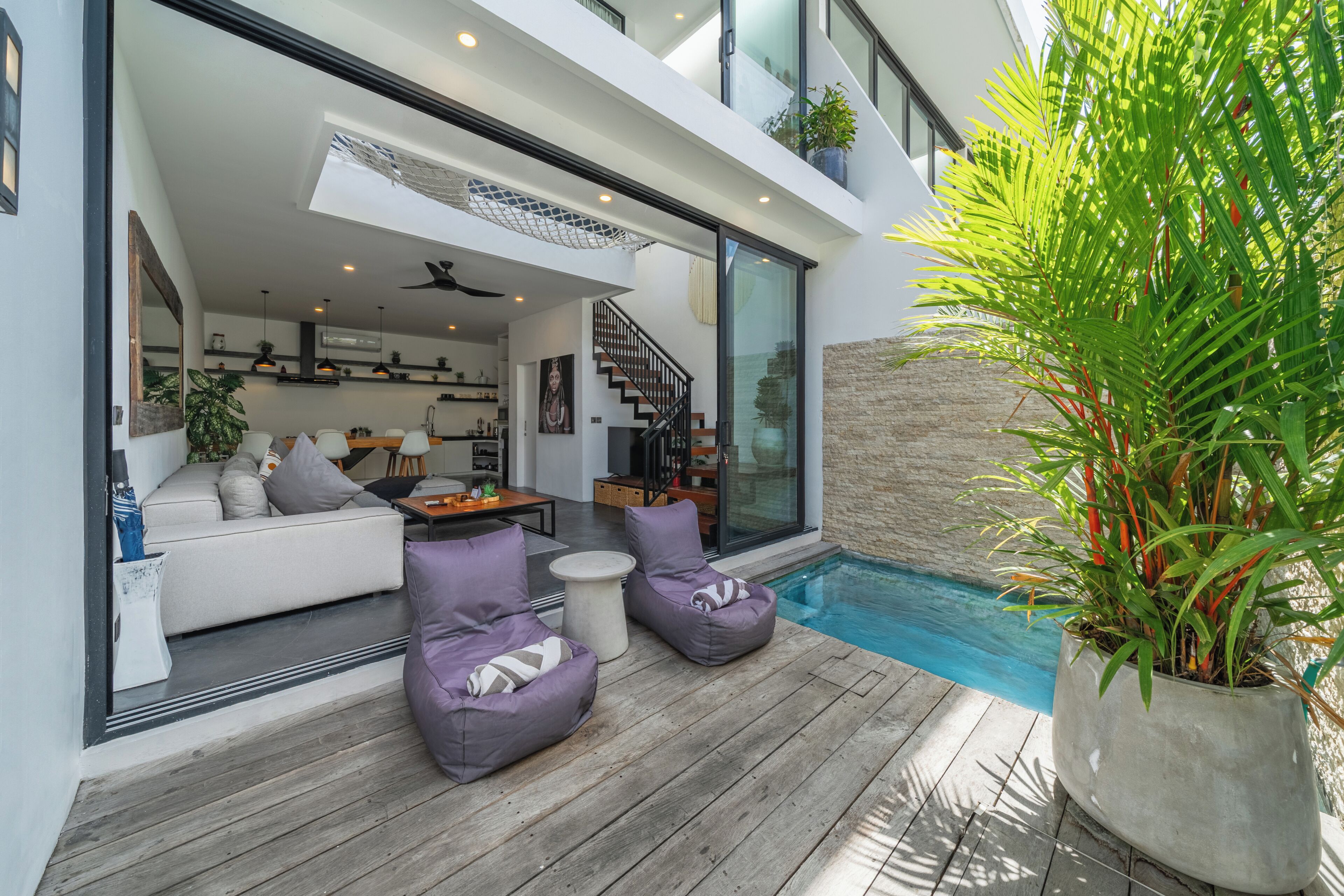 Ein moderner Außenbereich mit Pool, Sitzgelegenheiten und einer Treppe zu einer erhöhten Ebene.