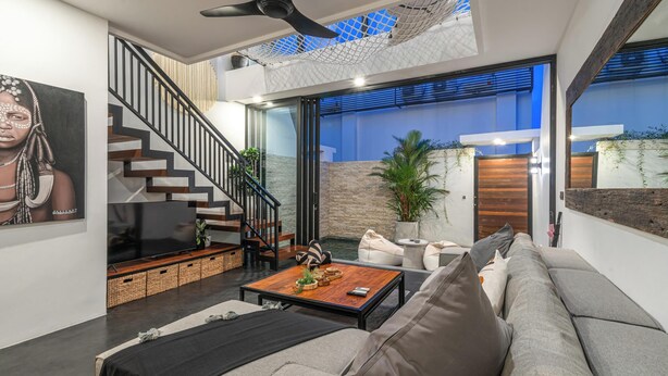 A modern living room with a staircase, a flat-screen TV, a coffee table, and a sofa. - Loft Erika (Canggu)
