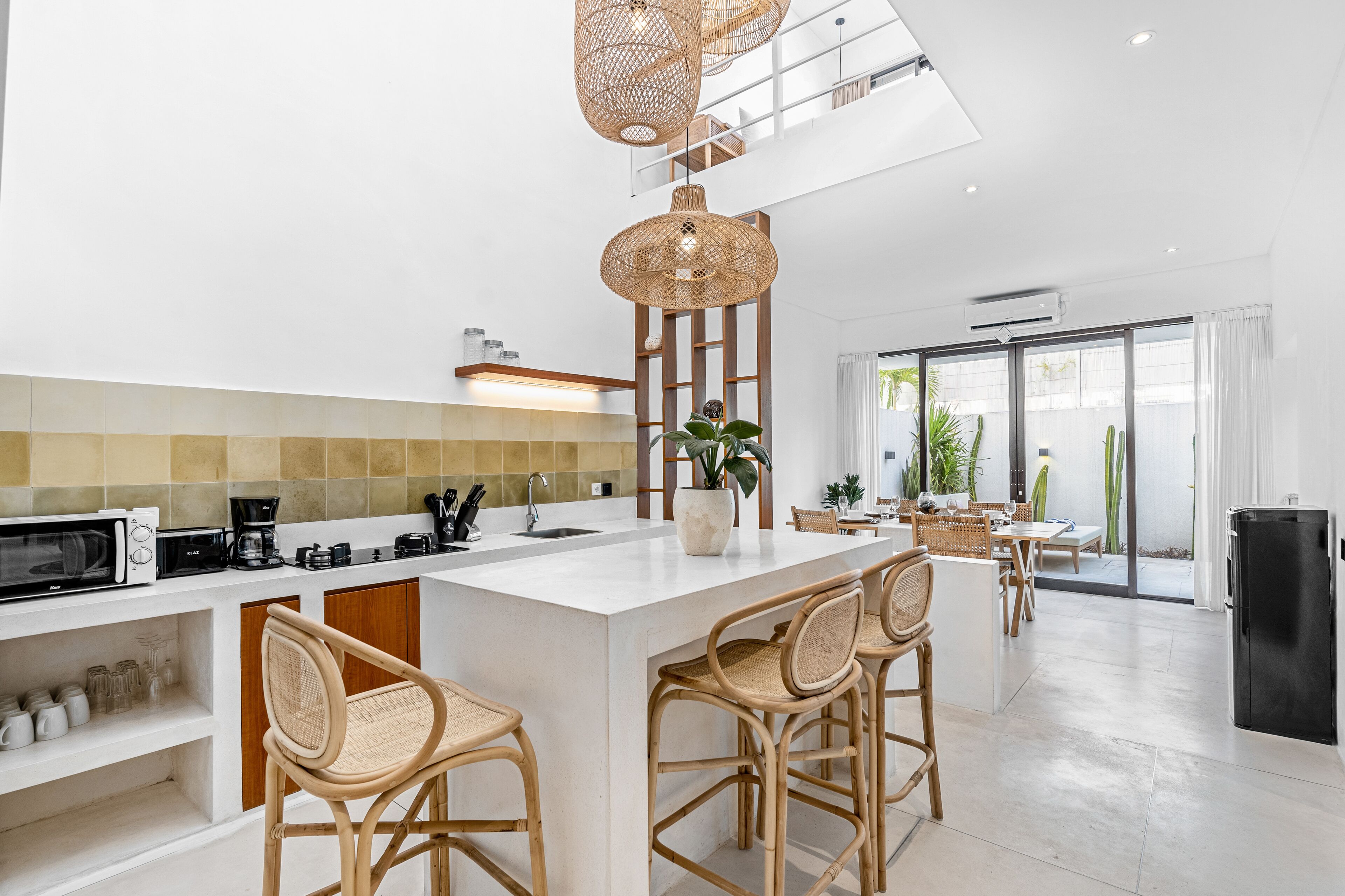 Une cuisine moderne dotée d’un îlot central, de tabourets de bar et d’un coin repas avec une table et des chaises.