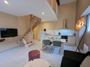 Un appartement moderne doté d’un escalier en bois, d’un coin repas, d’une cuisine et d’un salon avec un téléviseur à écran plat.