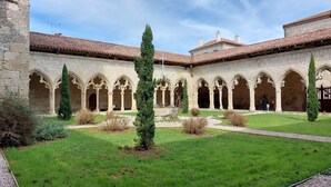 Un patio con un edificio de piedra que presenta arcadas y un techo de tejas.