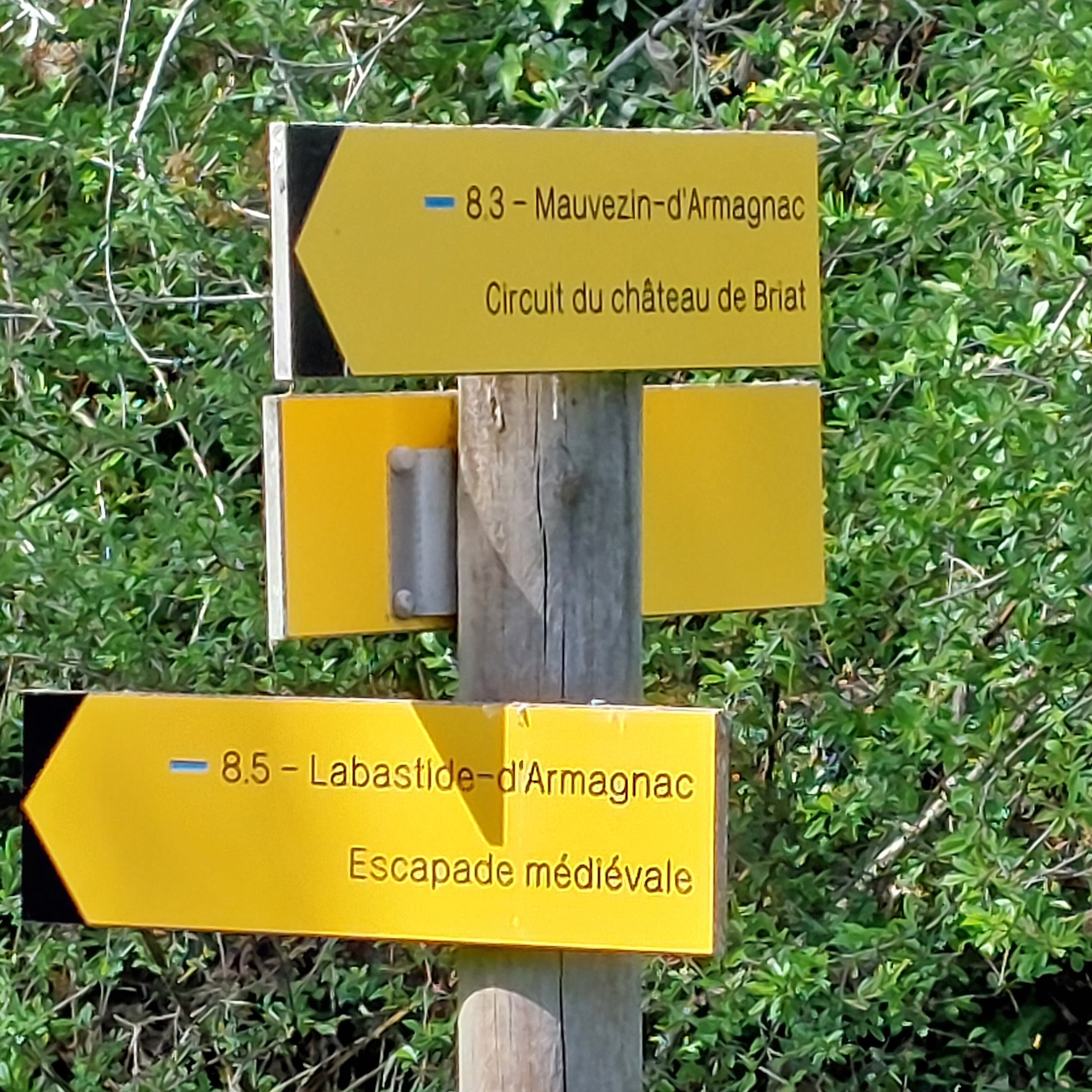 A directional signpost with two yellow signs pointing to historical sites.
