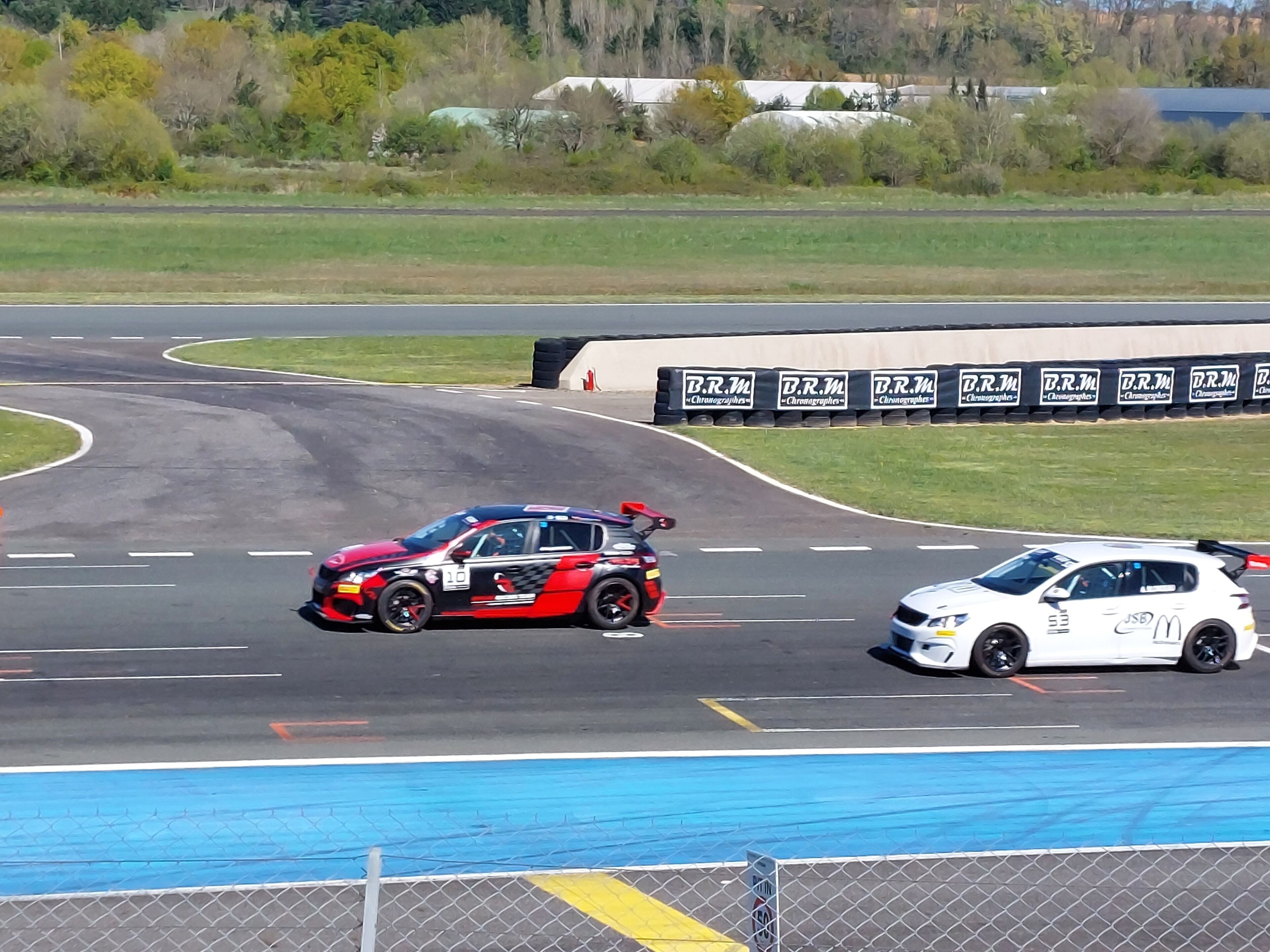 Une piste de course avec deux voitures, une rouge et une blanche, qui s'affrontent sur la piste.