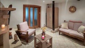 A cozy living room with a wooden sofa, striped armchair, and a small table with a vase.
