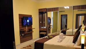 A hotel room with a bed, a television, a mirror, and a bedside table with a lamp. - HAVEN TOWER (Manama)