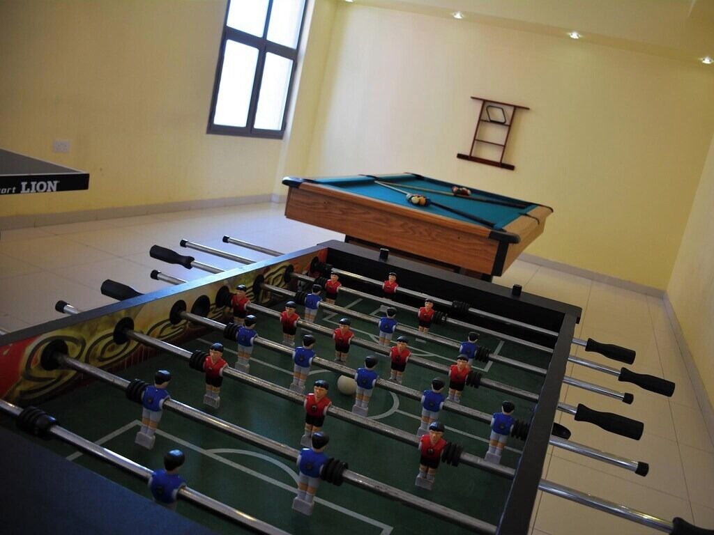 Una mesa de fútbol de mesa en una habitación con una mesa de billar y un ventanal.