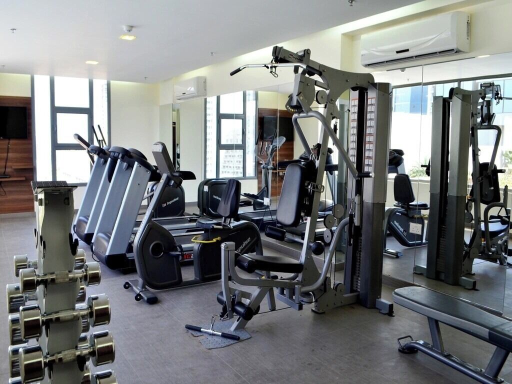 A gym with various exercise equipment, including treadmills, weight machines, and dumbbells.