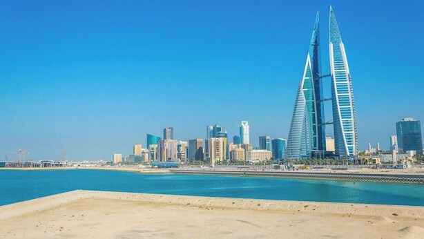 A coastal cityscape with modern skyscrapers, including two prominent towers with a unique design. - HAVEN TOWER (Manama)