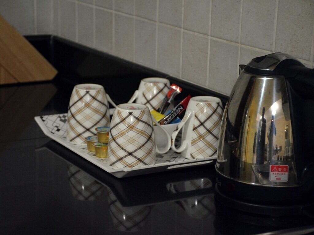 A kitchen counter with a tray holding several mugs and a kettle.