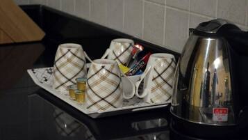 A kitchen counter with a tray holding several mugs and a kettle.