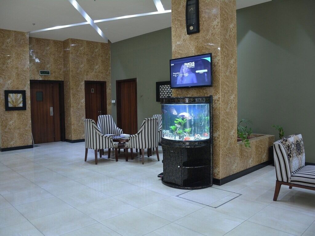 En entréhall med ett akvarium, en sittgrupp och en tv som är monterad på en pelare.