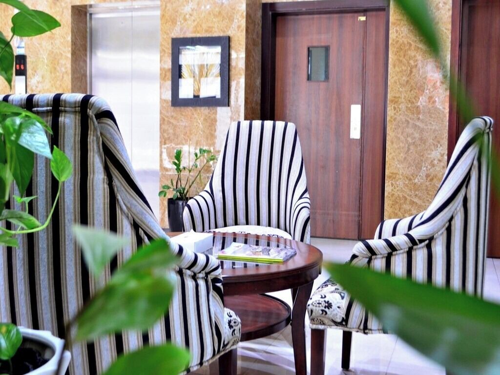 A seating area with striped chairs and a table, a door, and a potted plant.