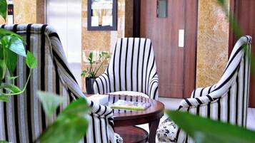A seating area with striped chairs and a table, a door, and a potted plant.