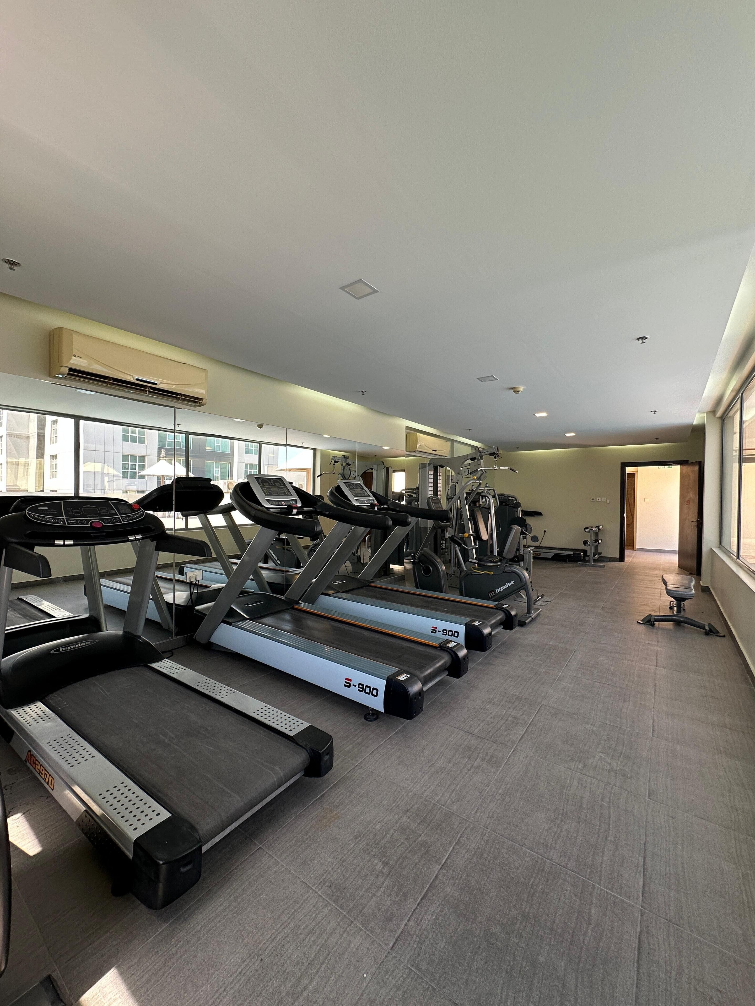 A gym with treadmills, exercise bikes, and weight machines.