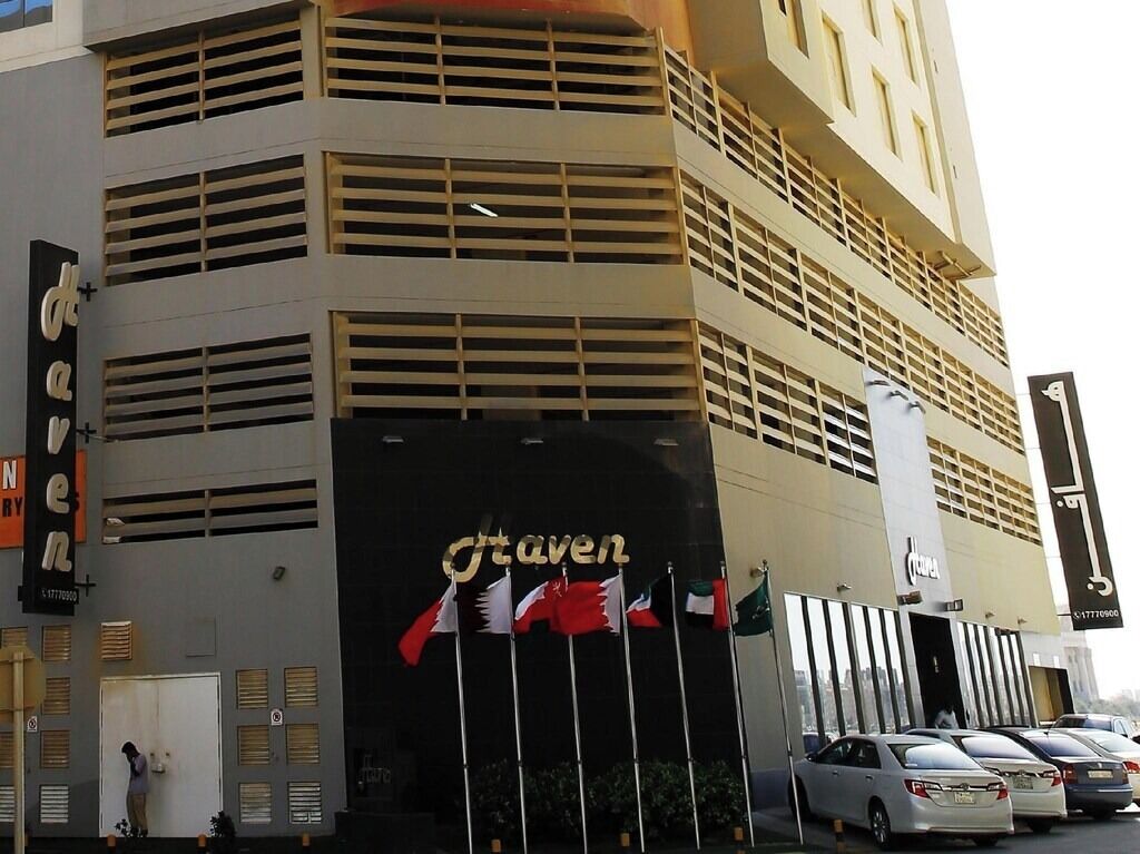 A hotel with a prominent 'Staven' sign, multiple flags, and a modern architectural design.