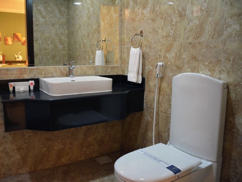 A modern bathroom with a white sink, black countertop, and a white toilet.