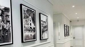 A hallway with framed black and white photographs on the wall, a patterned carpet, and a white door at the end. - Hotel Wonder Hills @ Har ki Pauri Road Haridwar (Haridwar)