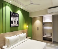 A hotel room with a bed, a wardrobe, a ceiling fan, and a wall-mounted air conditioner.