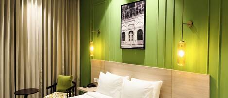 A hotel room with a large bed, a nightstand with a phone and remote, a chair, and a wall-mounted picture.